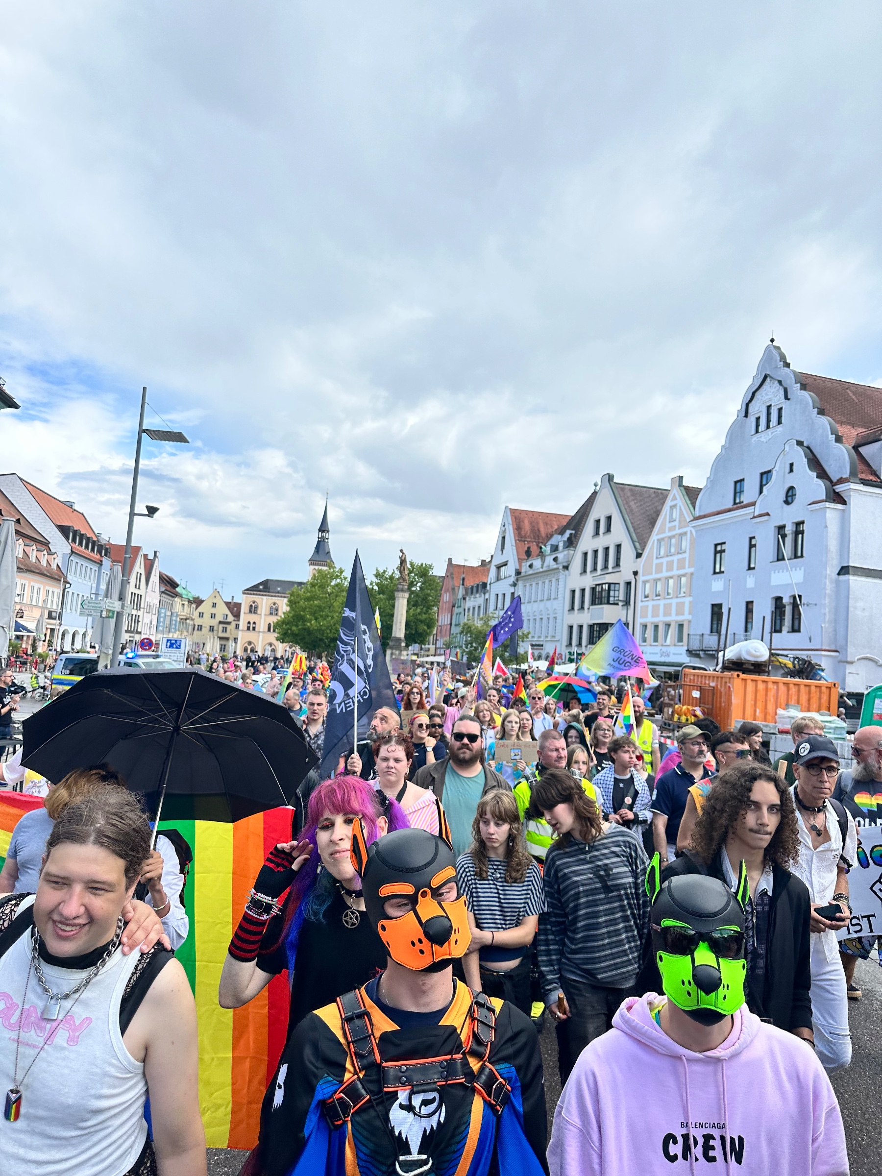 Blick auf die CSD-Parade mit vielen Teilnehmenden und bunten Flaggen vor den Häusern der Pfaffenhofener Innenstadt.