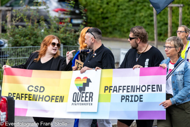 Teilnehmende tragen das CSD-Pfaffenhofen-Banner mit Regenbogenfarben und Vereinslogo bei der Parade.