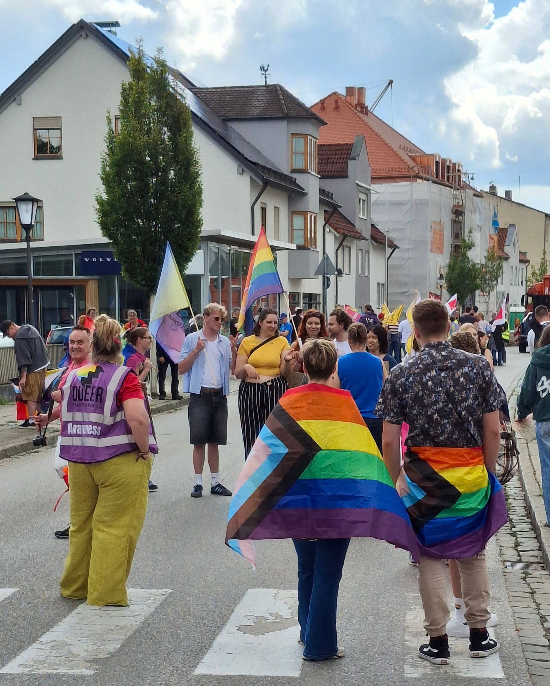 Teilnehmende mit umgelegten Pride-Flaggen gehen durch die Pfaffenhofener Innenstadt.